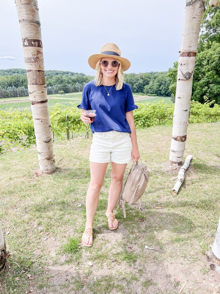 Navy ruffled sleeve shirt and white shorts at winery.