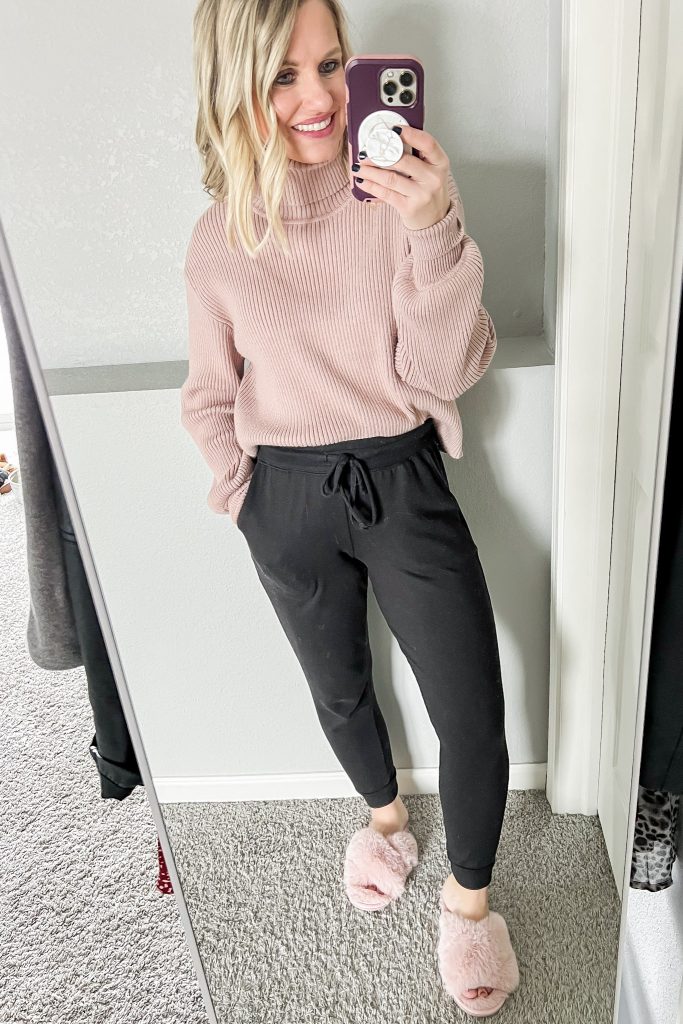 Pink turtleneck sweater with joggers and slippers.
