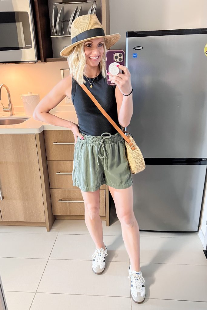 Casual day time outfit for a cruise vacation with green shorts and a black tank top.