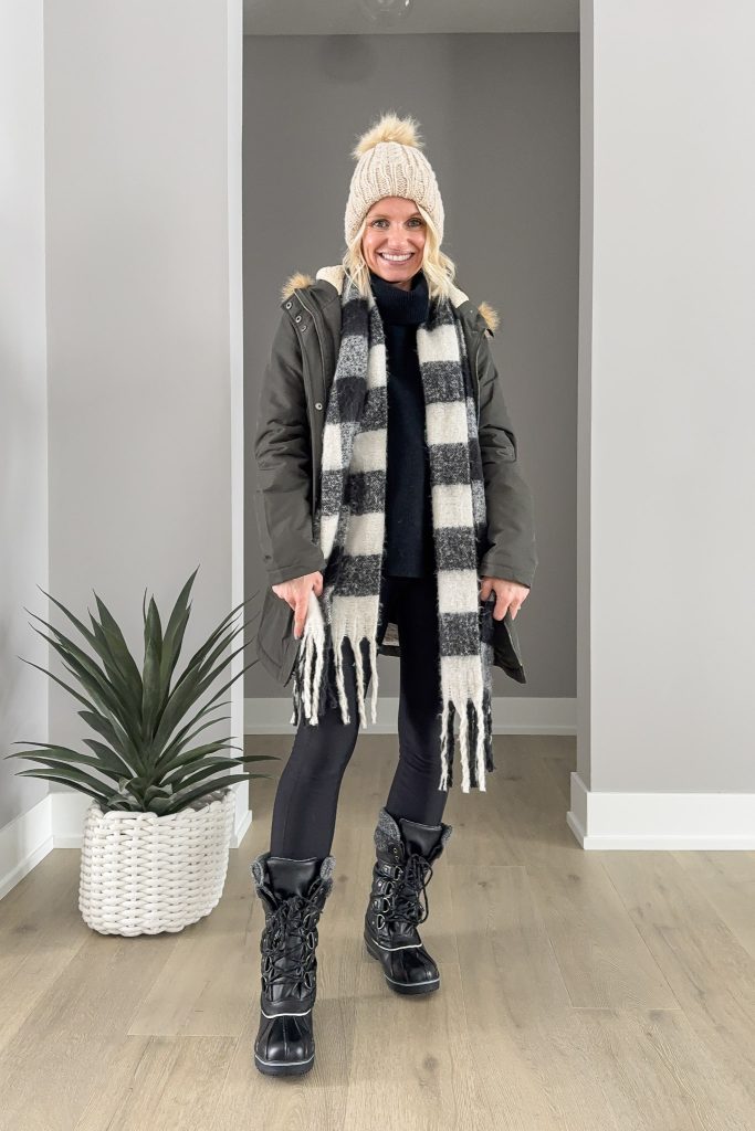 Plaid scaft paired with a green coat, boots and a hat.
