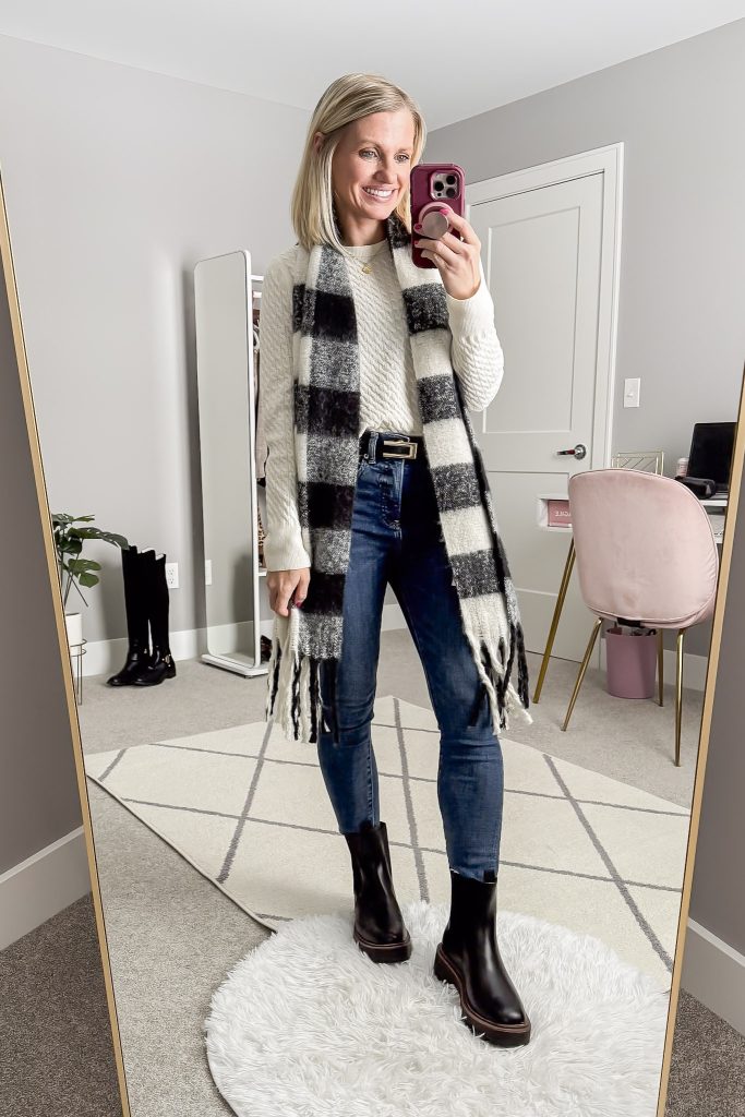 Cream cable knit sweater with skinny jeans boots and a plaid scarf.